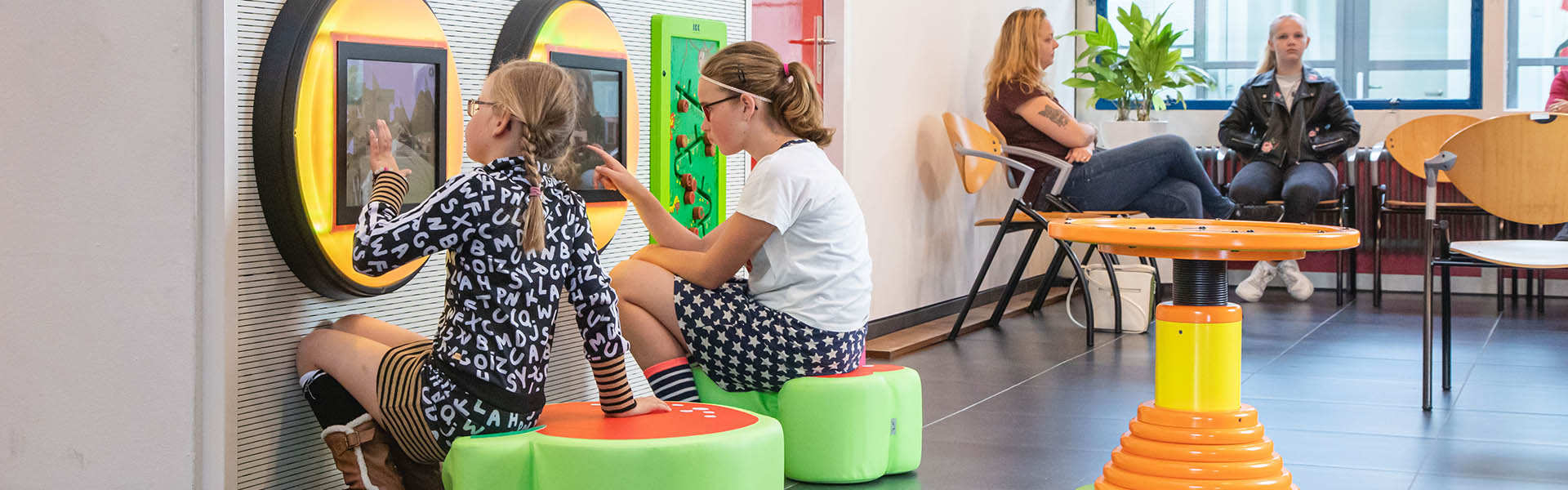 Op deze afbeelding ziet u kinderen spelen in een kinderhoek in een ziekenhuis